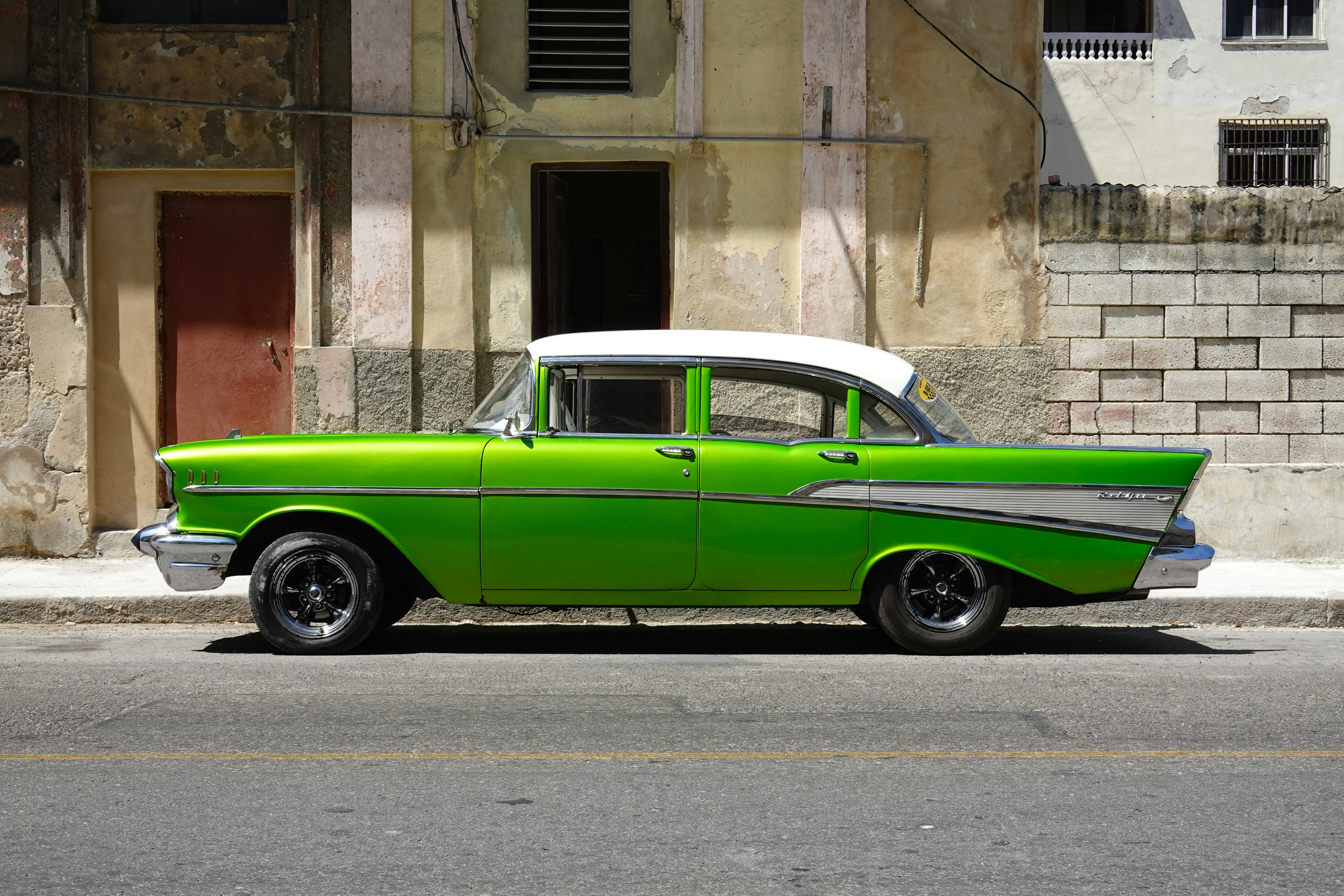 green car parked beside brown concrete building during daytime